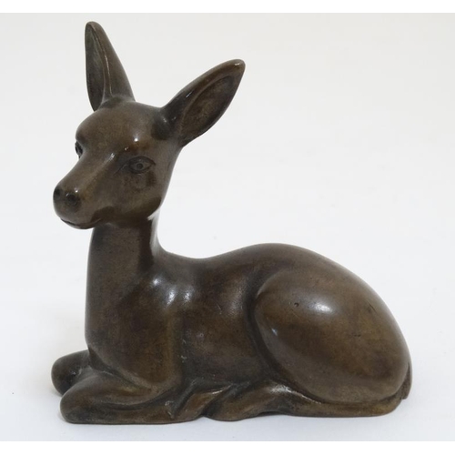 826 - A mid 20thC cast solid bronze figure of a seated doe deer. 3 1/2'' high