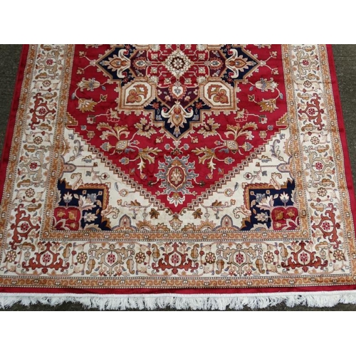 83 - Carpet / Rug : A machine made woollen rug with red and buff central ground, surrounded with midnight... 