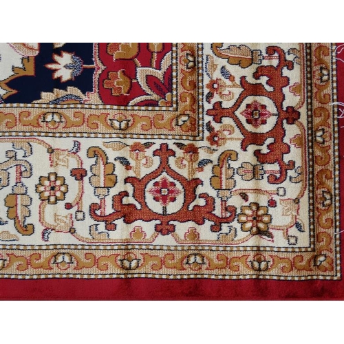 83 - Carpet / Rug : A machine made woollen rug with red and buff central ground, surrounded with midnight... 