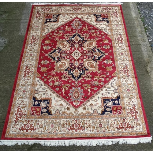 83 - Carpet / Rug : A machine made woollen rug with red and buff central ground, surrounded with midnight... 