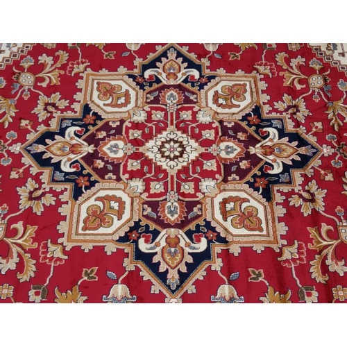 83 - Carpet / Rug : A machine made woollen rug with red and buff central ground, surrounded with midnight... 