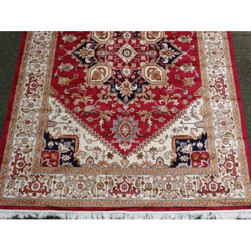 83 - Carpet / Rug : A machine made woollen rug with red and buff central ground, surrounded with midnight... 