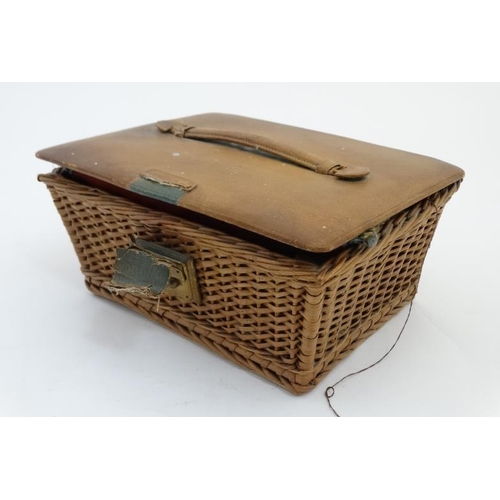 879 - An early 20thC sewing basket with wicker base and leather covered top, opening to reveal green leath... 