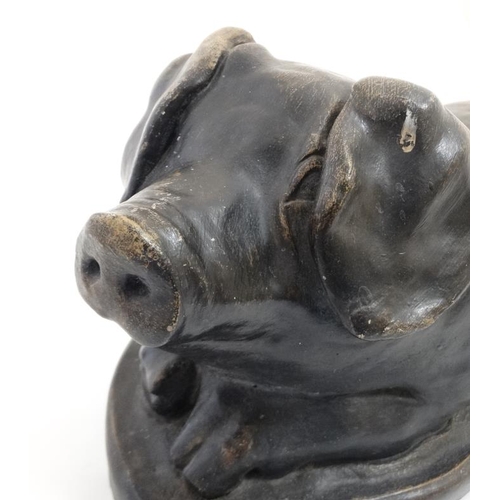 891 - A mid / late 20thC black painted reconstituted stone model of a recumbent pig 19 1/2'' long x 9 1/4'... 