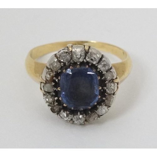 932 - An 18ct gold ring set with central sapphire bordered by diamonds