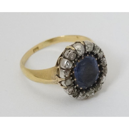 932 - An 18ct gold ring set with central sapphire bordered by diamonds