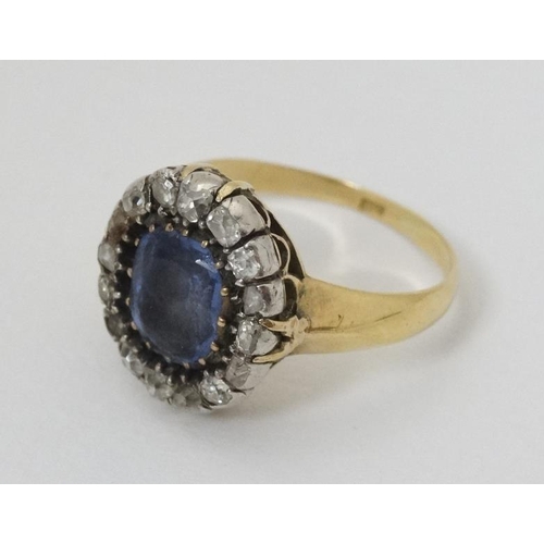 932 - An 18ct gold ring set with central sapphire bordered by diamonds