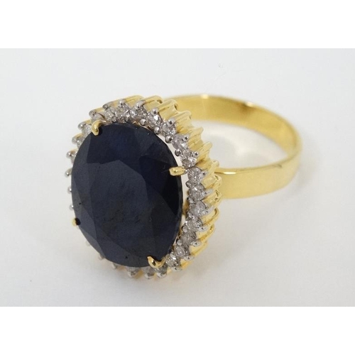 948 - A 14ct gold ring set with large blue sapphire bordered by diamonds. The whole 3/4'' x 5/8''