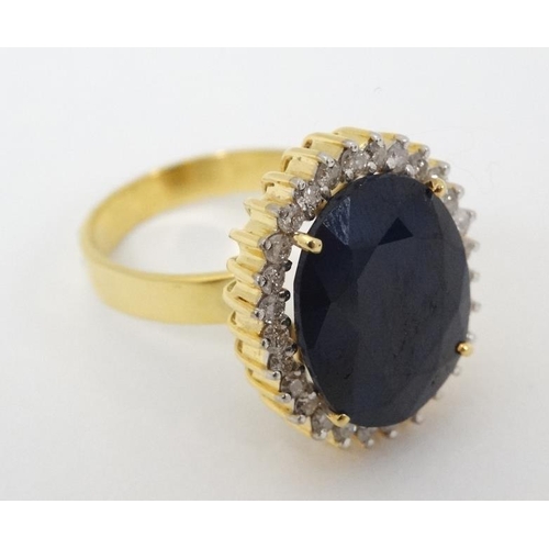 948 - A 14ct gold ring set with large blue sapphire bordered by diamonds. The whole 3/4'' x 5/8''