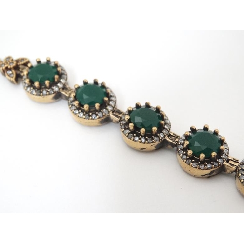 964 - A silver bracelet set with green and white stones with gilt decoration