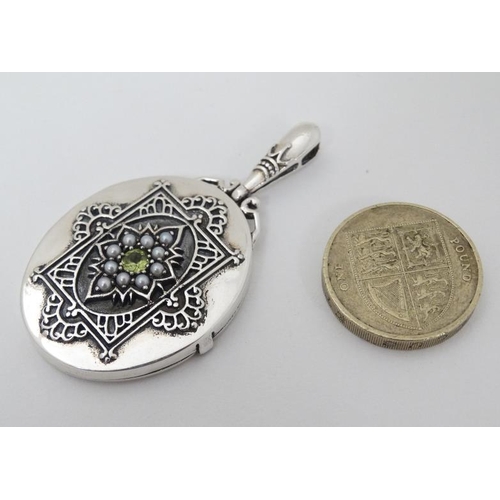 975 - A white metal pendant locket set with central peridot 2'' long