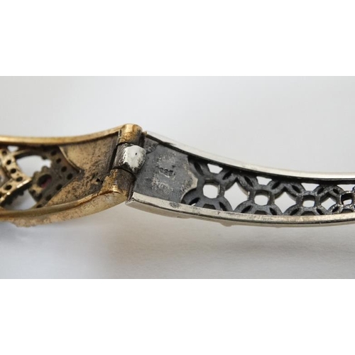 977 - A silver bracelet with silver gilt decoration and set with blue red and white stones