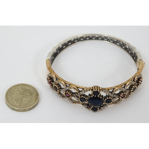 977 - A silver bracelet with silver gilt decoration and set with blue red and white stones