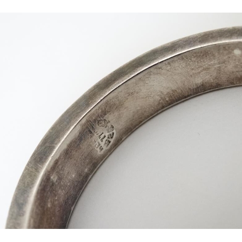 984 - A Mexican silver bracelet of bangle form together with a pair of silver hoop earrings