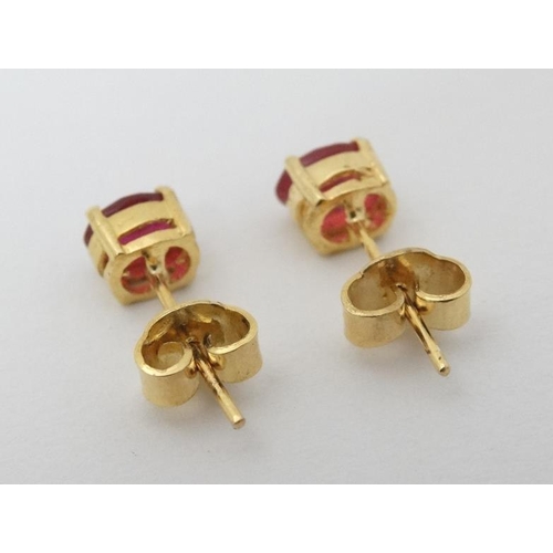 987 - A pair of gilt metal stud earrings set with red stones.