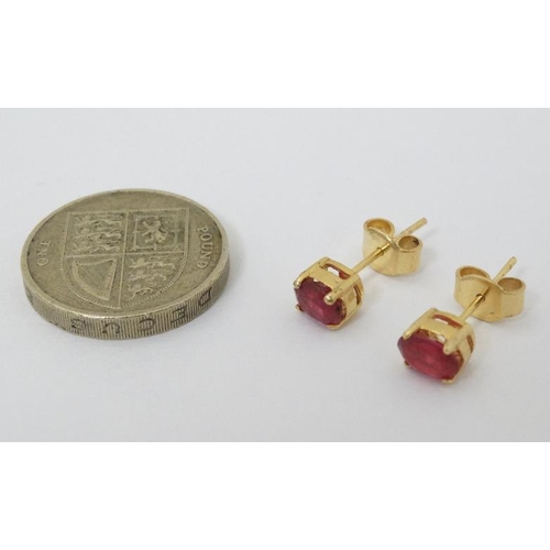 987 - A pair of gilt metal stud earrings set with red stones.