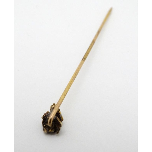 990 - A gilt metal stick pin surmounted by gold nugget style decoration set with semi previous? stone the ... 