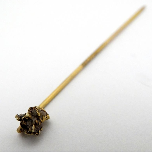 990 - A gilt metal stick pin surmounted by gold nugget style decoration set with semi previous? stone the ... 