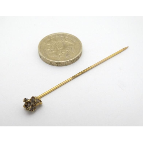 990 - A gilt metal stick pin surmounted by gold nugget style decoration set with semi previous? stone the ... 