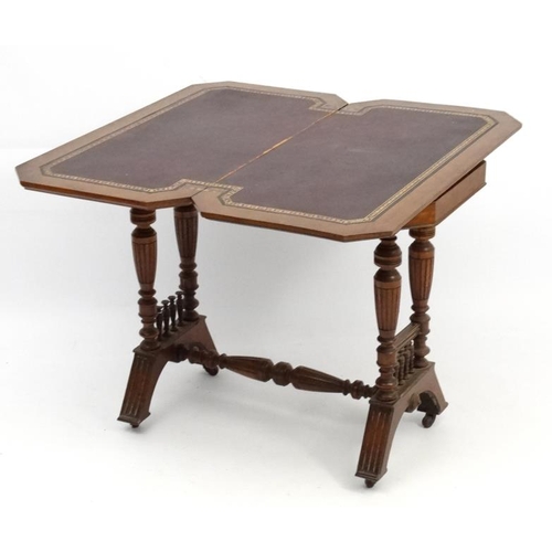 191 - A Victorian stained oak card table with fold over and twist top and gold tooled burgundy leather ins... 