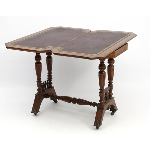 191 - A Victorian stained oak card table with fold over and twist top and gold tooled burgundy leather ins... 