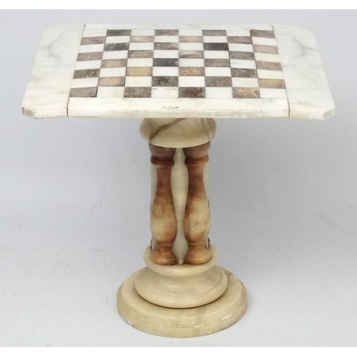 220 - A 20thC onyx engraved marble veined games table with checker board top on pedestal column 23 1/2'' l... 