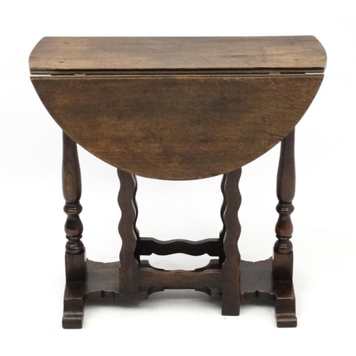 255 - An early - mid 20thC oak peg jointed oval drop flap occasional table with twin gatelegs 25 3/4'' hig... 