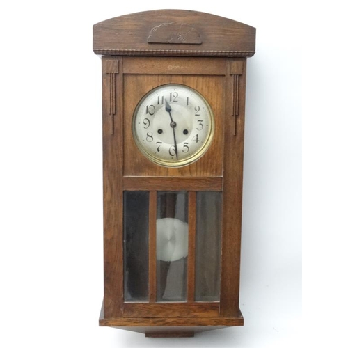 301 - 1930's Oak cased Wall Clock : an 8 day pendulum clock  with pine cone logo , striking on a coiled go... 