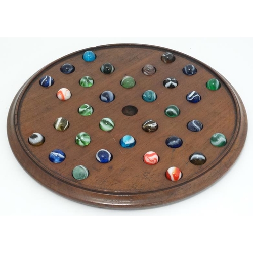 385 - Toy: A 19thC mahogany solitaire board with 32 coloured handmade marbles.  Please Note -  we do not m... 