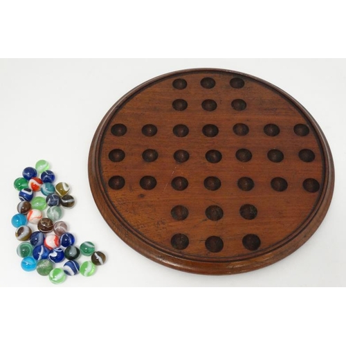 385 - Toy: A 19thC mahogany solitaire board with 32 coloured handmade marbles.  Please Note -  we do not m... 