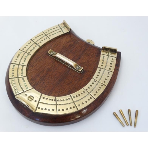 388 - A medium brass cribbage board formed as a horseshoe, with four pegs and mounted upon a wooden plinth... 