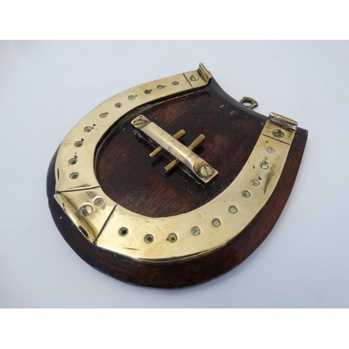 389 - A small brass cribbage board formed as a horseshoe, with two pegs and mounted upon a wooden plinth. ... 