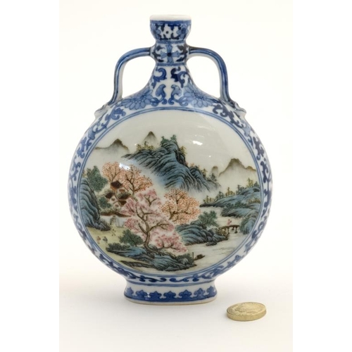 414 - A small blue and white Chinese twin handled moon flask, painted in blue with lotus scrolls and the t... 