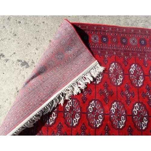 79 - Rug / Carpet :   A woollen Bokara Rug with wine red ground and 4 x 11 (44) botehs to center ,  99 x ... 