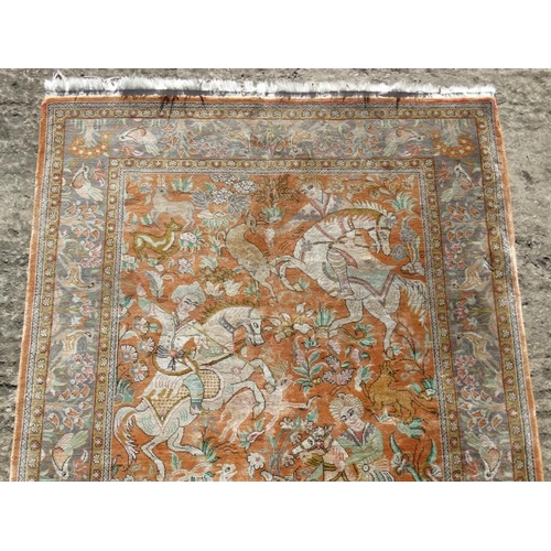 80 - Carpet / Rug :  a silk Floss rug having a pale rust ground with hunting scene of 5 figures on horseb... 