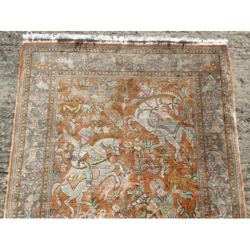 80 - Carpet / Rug :  a silk Floss rug having a pale rust ground with hunting scene of 5 figures on horseb... 