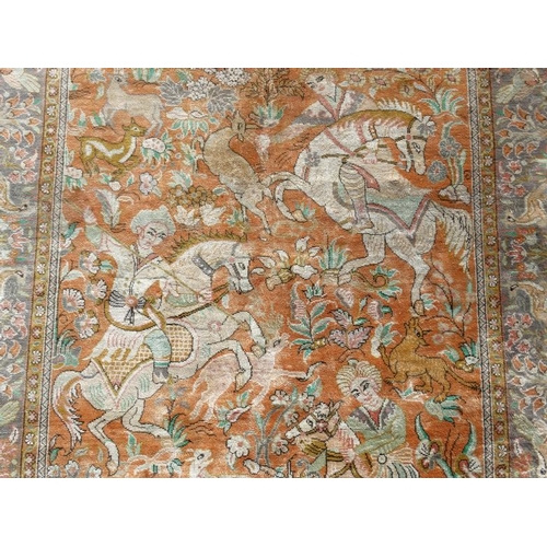 80 - Carpet / Rug :  a silk Floss rug having a pale rust ground with hunting scene of 5 figures on horseb... 