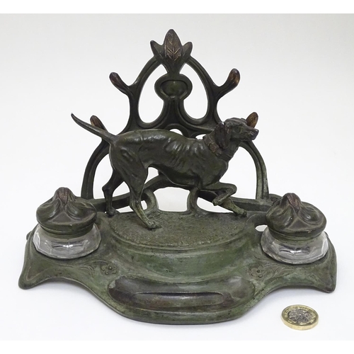 147 - An early - mid 20thC spelter Standish with dog and stylised Art Nouveau foliate decoration with twin... 