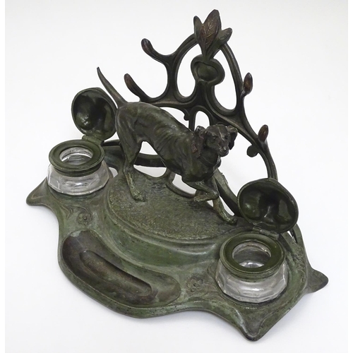 147 - An early - mid 20thC spelter Standish with dog and stylised Art Nouveau foliate decoration with twin... 