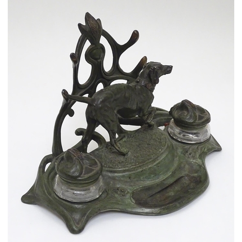 147 - An early - mid 20thC spelter Standish with dog and stylised Art Nouveau foliate decoration with twin... 