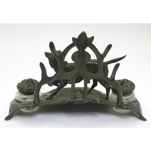 147 - An early - mid 20thC spelter Standish with dog and stylised Art Nouveau foliate decoration with twin... 