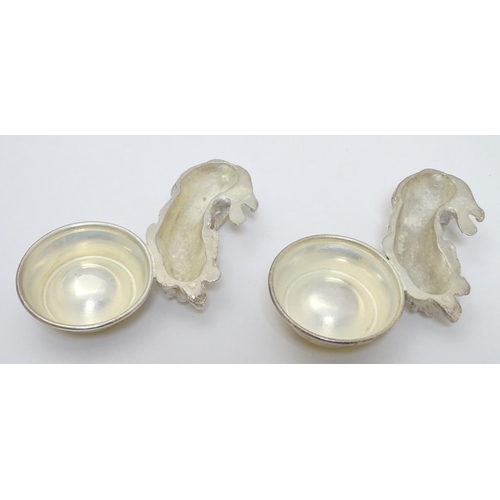 157 - A pair of Novelty silver plate salts formed as recumbent dogs before bowls. Approx 4 1/2''