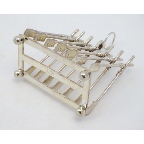 190 - Rowing: A novelty 6-slice silver plated toast rack, the bars formed as oars. 21stC  Approx 8'' high ... 