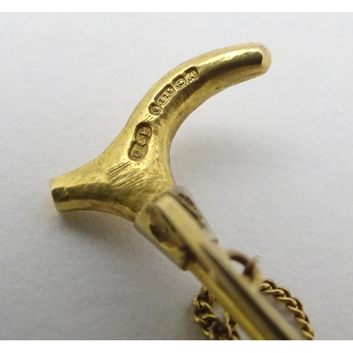 434 - A 9ct gold stock pin / brooch formed as a riding crop / whip with fox head decoration to centre. Hal... 