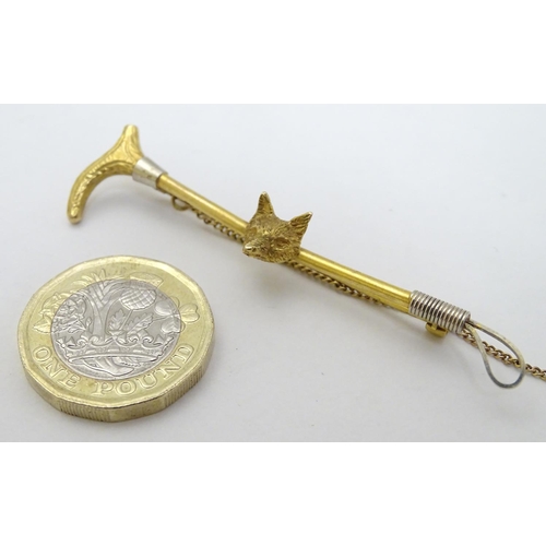 434 - A 9ct gold stock pin / brooch formed as a riding crop / whip with fox head decoration to centre. Hal... 