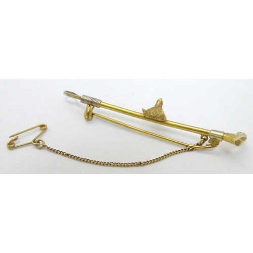 434 - A 9ct gold stock pin / brooch formed as a riding crop / whip with fox head decoration to centre. Hal... 