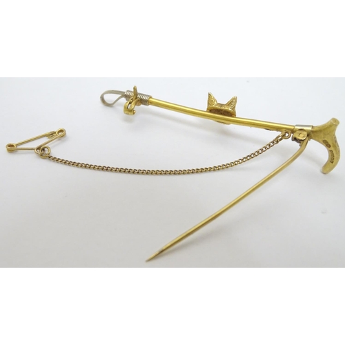 434 - A 9ct gold stock pin / brooch formed as a riding crop / whip with fox head decoration to centre. Hal... 