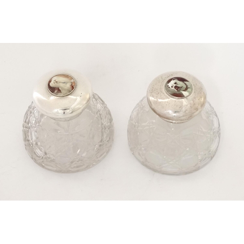 453 - Two cut glass inkwells having silver plated hinged tops with later applied cabochons depicting dogs ... 