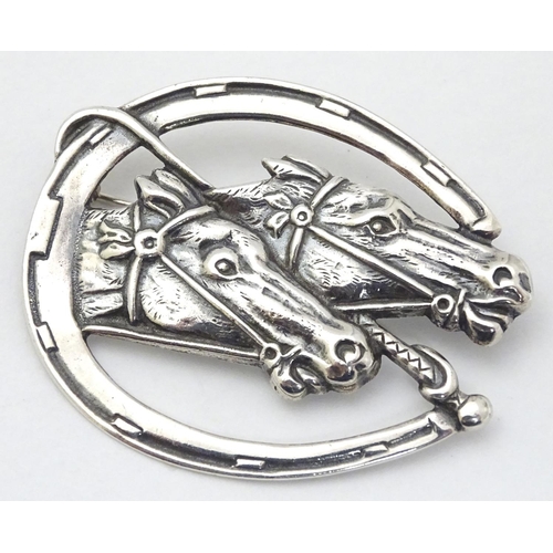 465 - A silver brooch formed as a horseshoe with riding crop / whip and horse head decoration. marked '925... 