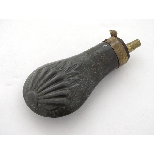 587 - Shooting: A 19thC pewter and brass pistol powder flask, having shell decoration and coil spring open... 